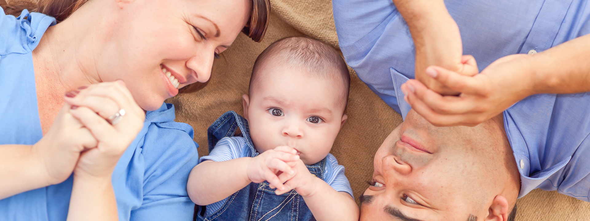 Mom and Dad on floor smiling at their baby on the floor between them