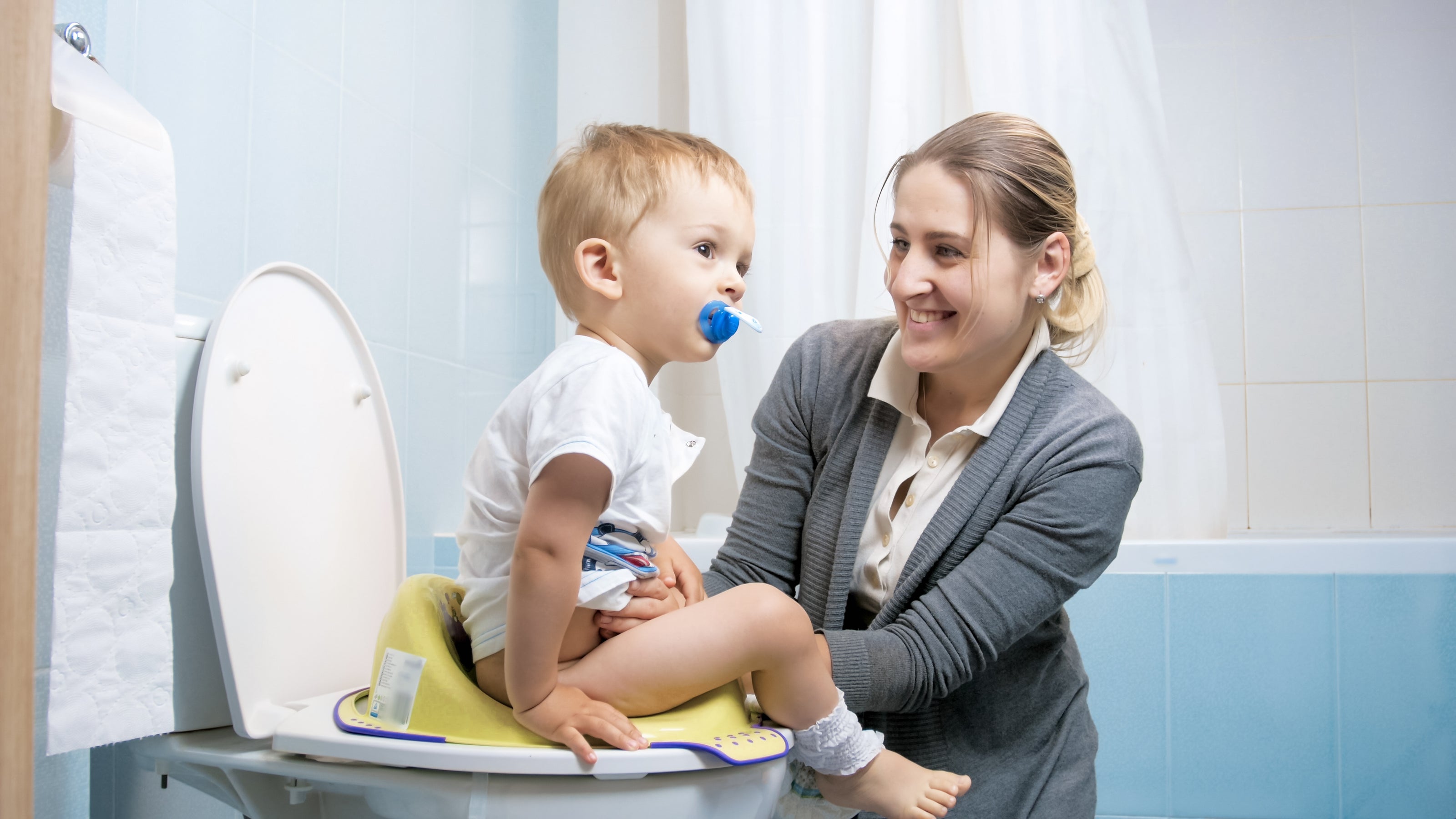 Happy mom helping her son potty train